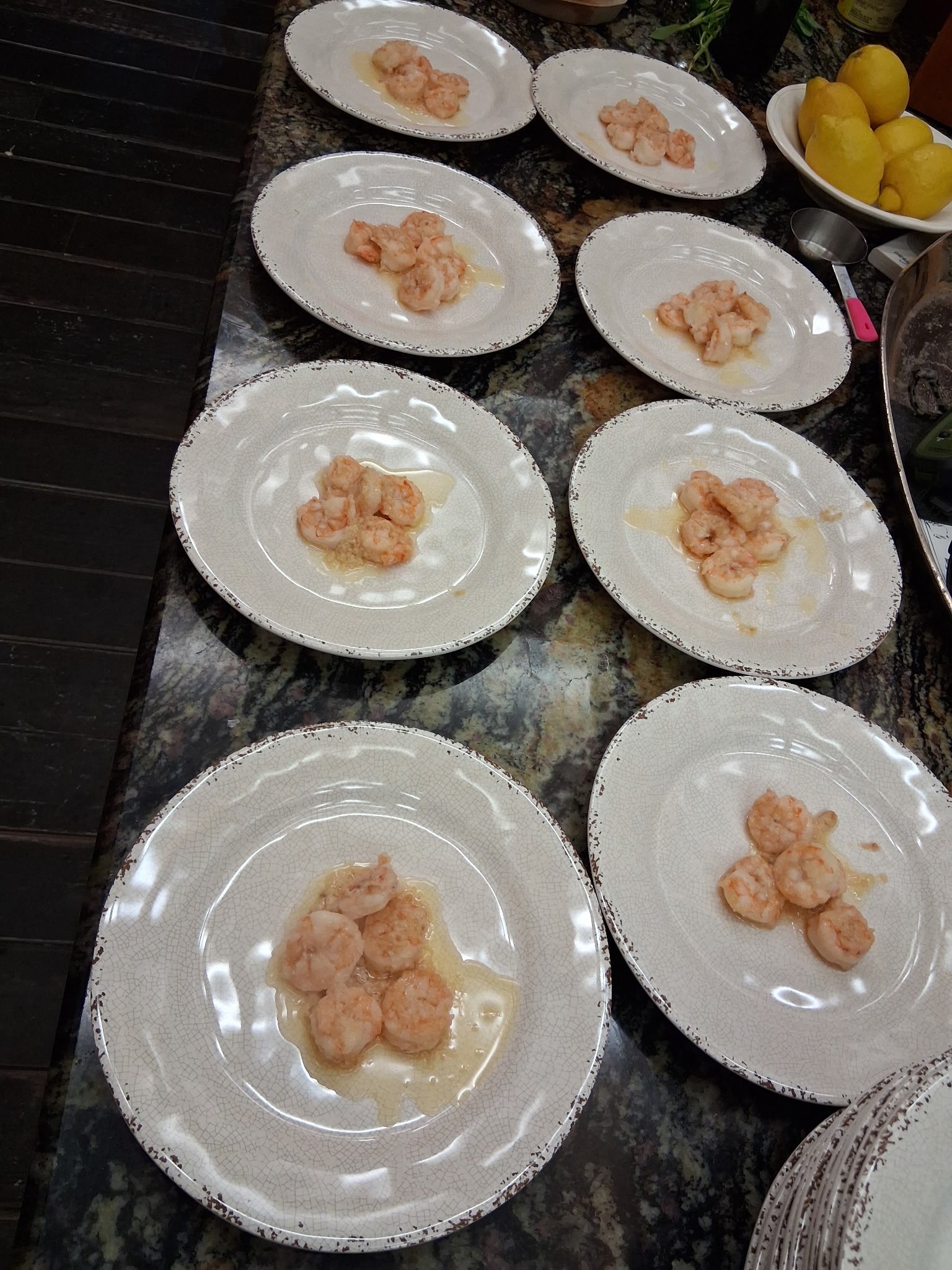 Rows of plated shrimp appetizers ready for service on a granite counter
