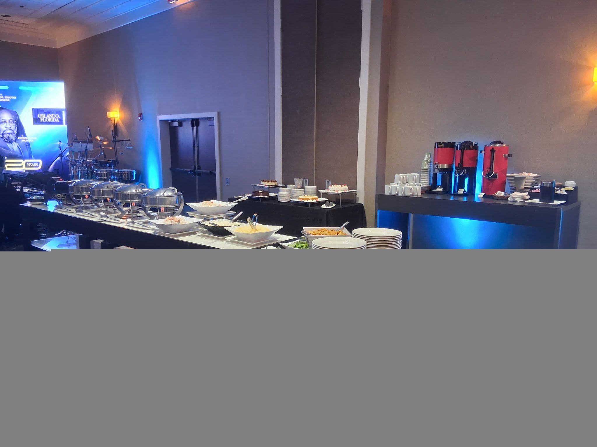 Corporate buffet and coffee station with silver chafing dishes and blue accent lighting