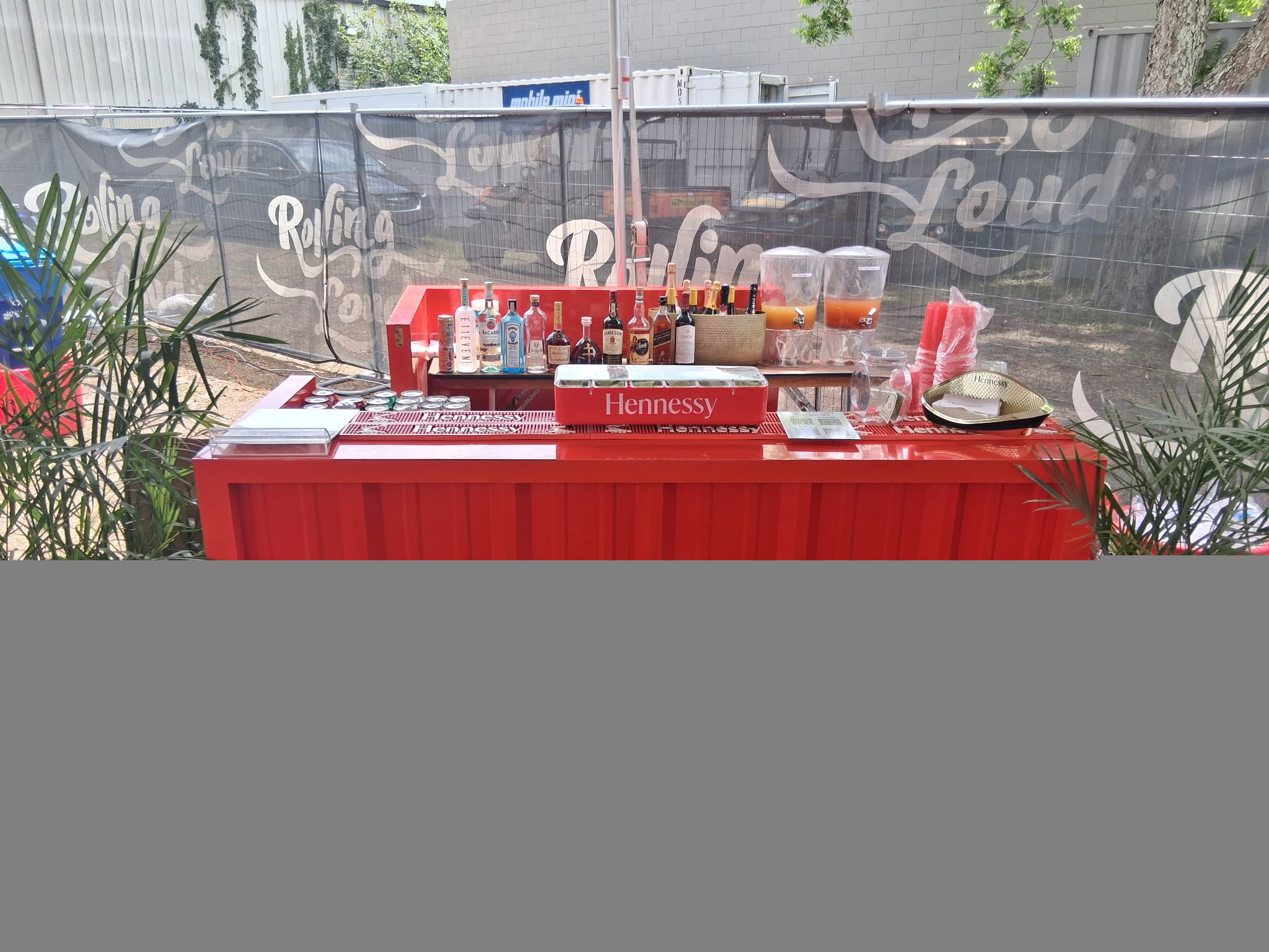 Red Hennessy-branded mobile bar stocked with premium spirits at an outdoor festival