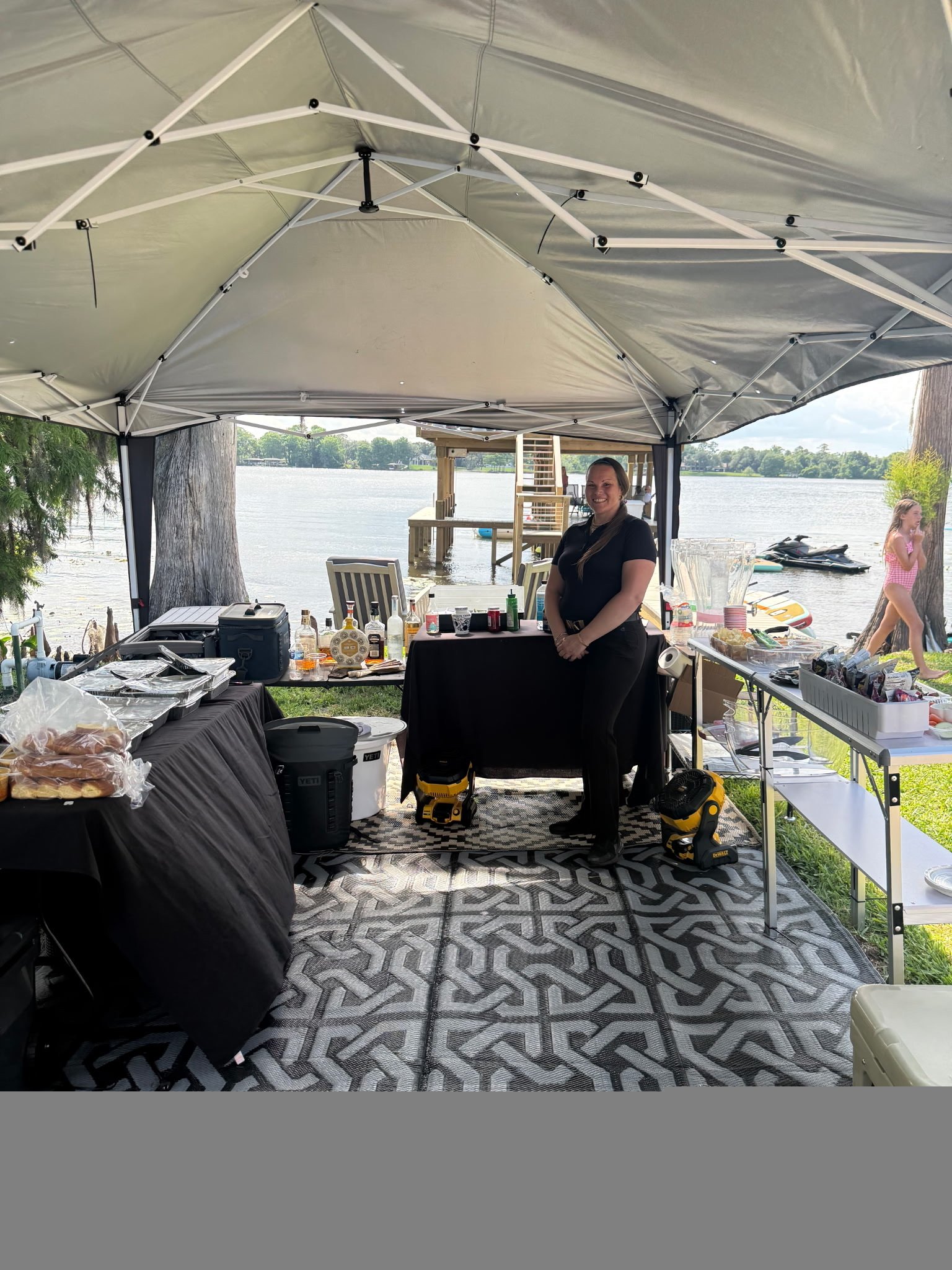 Lakeside bar and catering tent with a smiling staff member ready to serve