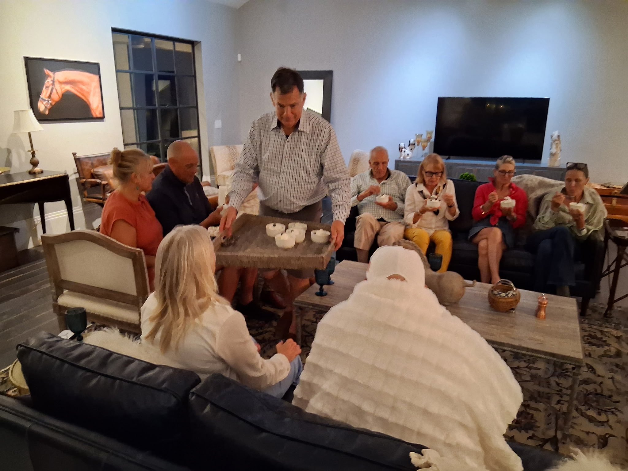 Server offering appetizer bowls to guests in a modern living-room gathering