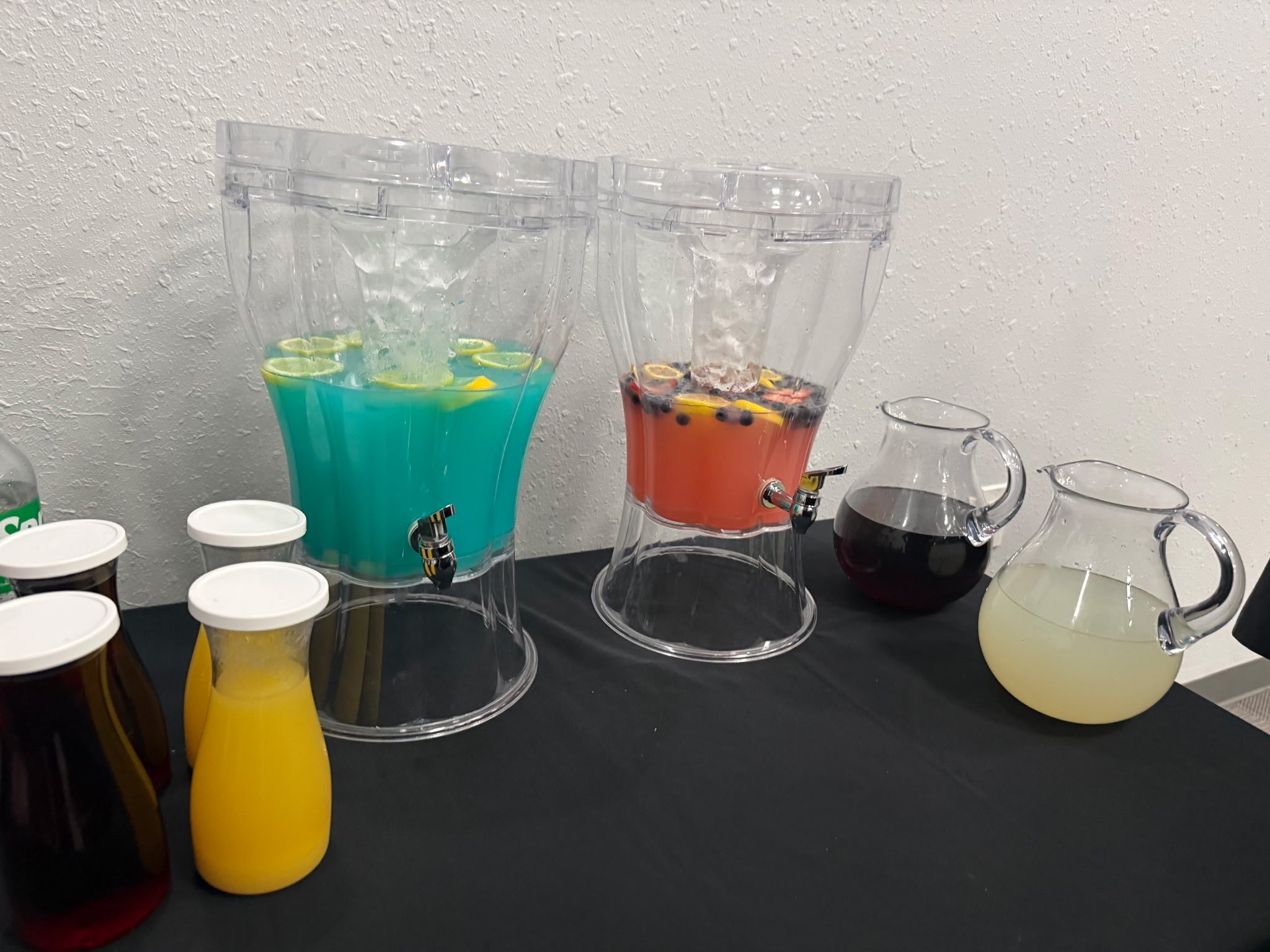 Colorful beverage station with teal and coral punch dispensers and juice carafes