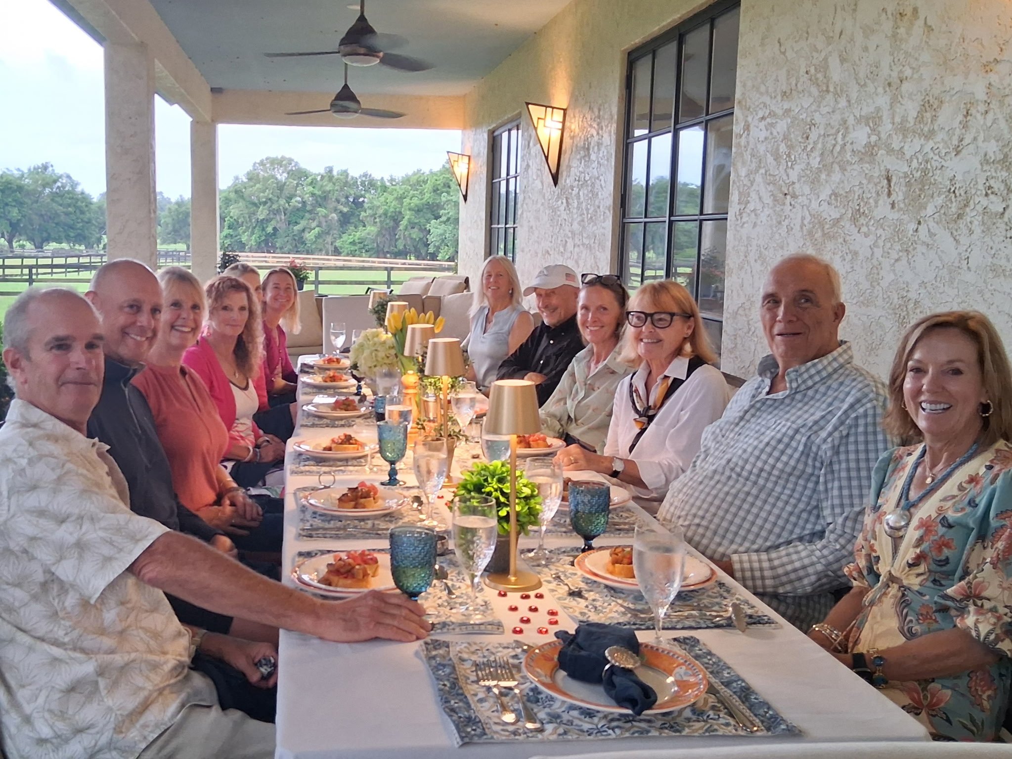 Guests seated at a long decorated outdoor dining table on a covered patio