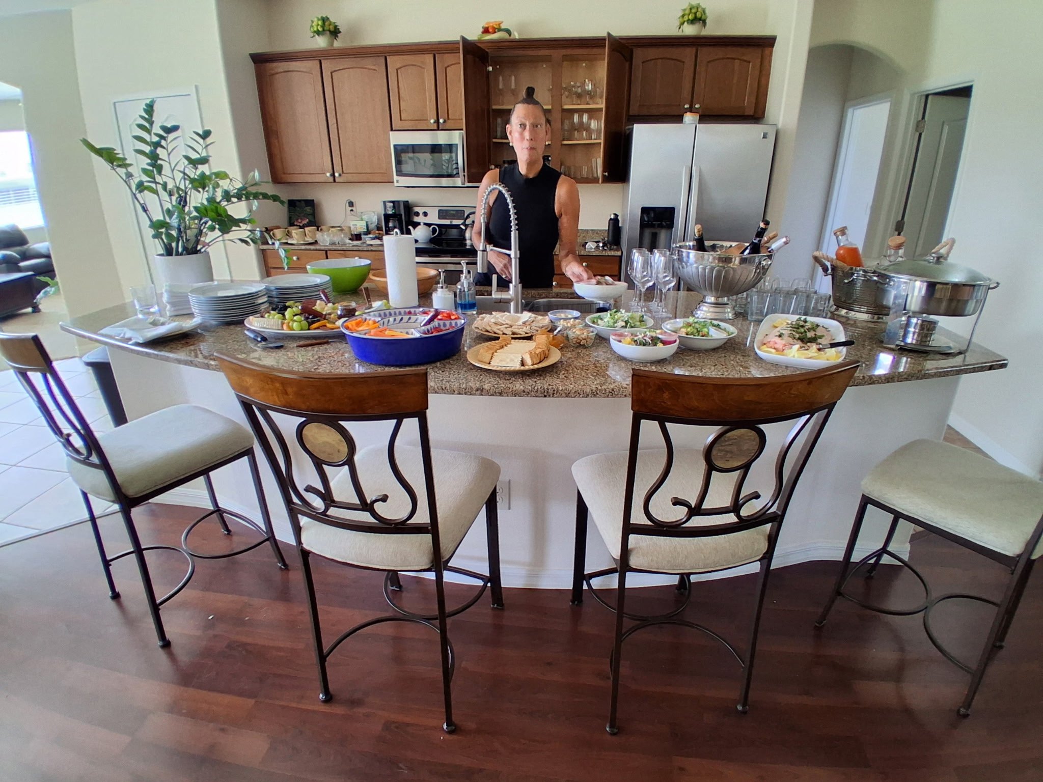 Home kitchen-island catering spread with appetizers and a server behind the counter