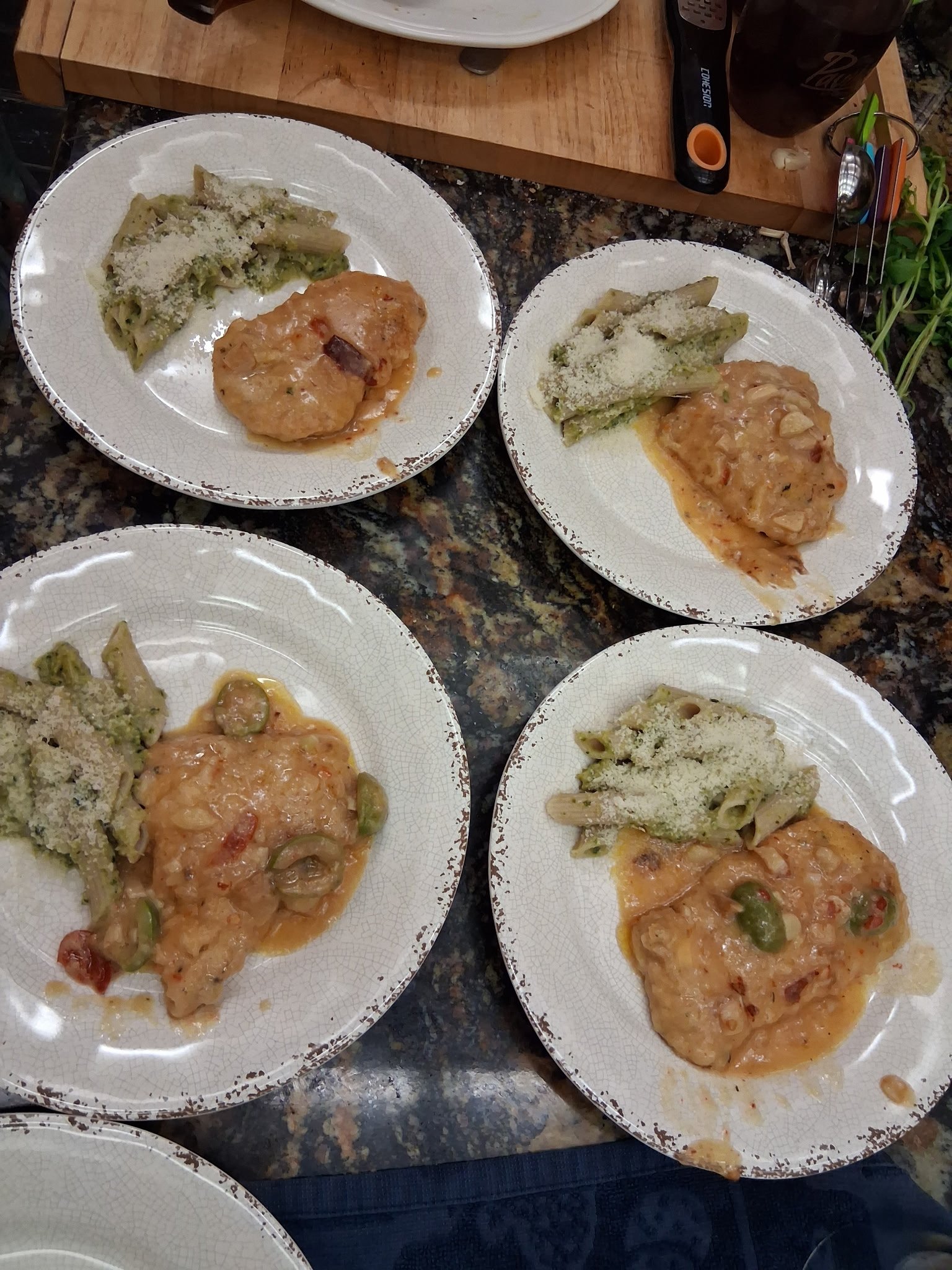 Plated chicken entrees with green vegetables lined up for guest service