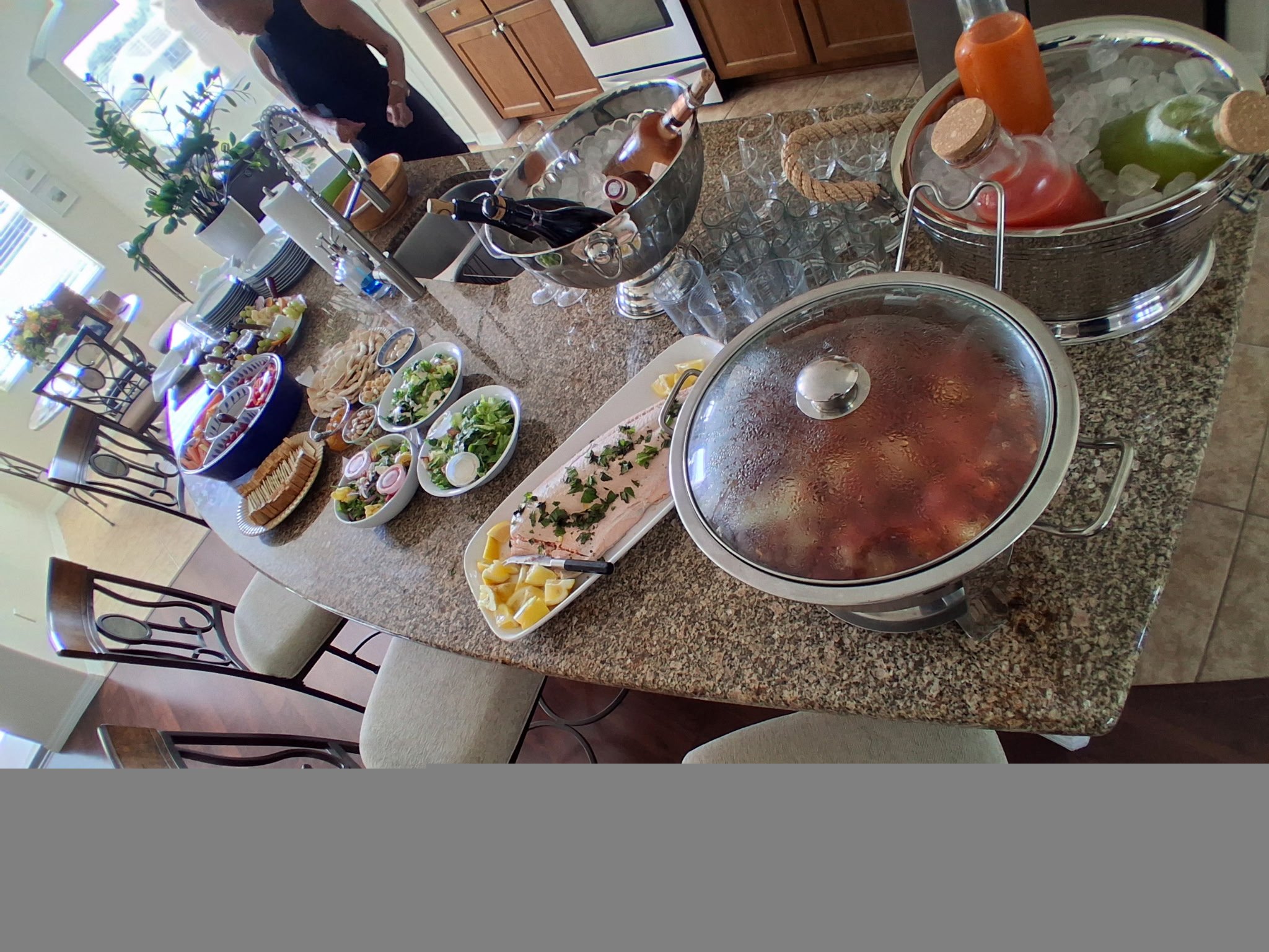 Kitchen-island feast with salmon, salads, wine on ice, and colorful juice carafes